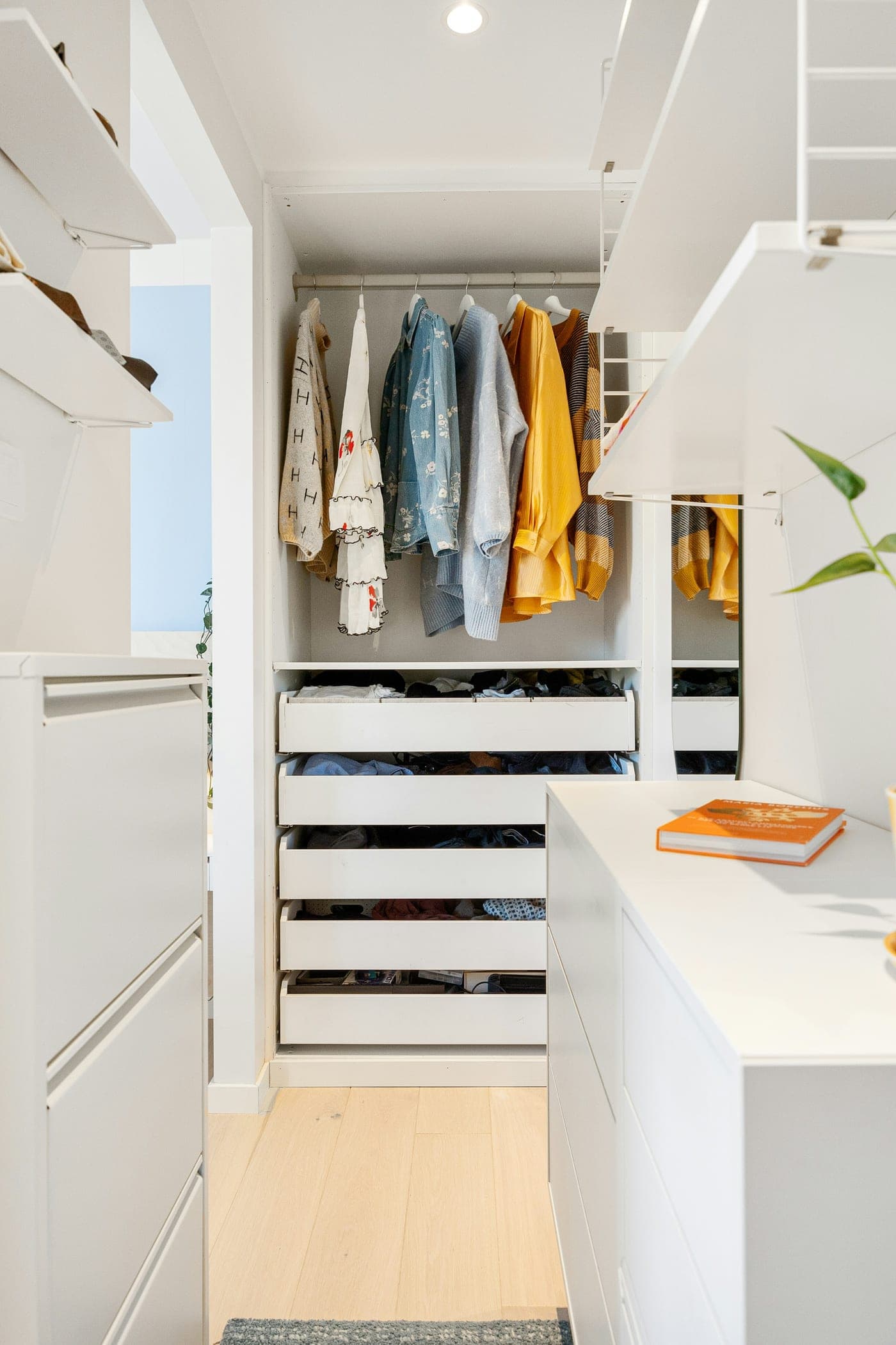 Closet planejado branco com gavetas abertas e cabideiro